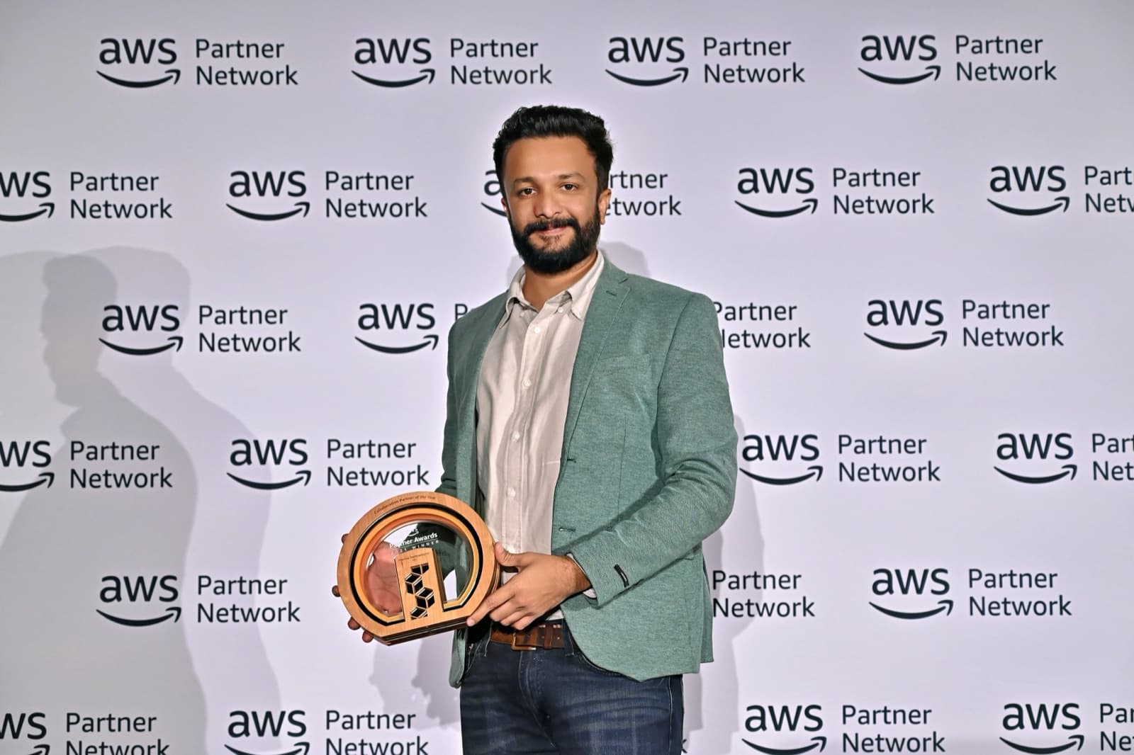 A Flentas leader holding an award in front of the AWS Partner Network backdrop