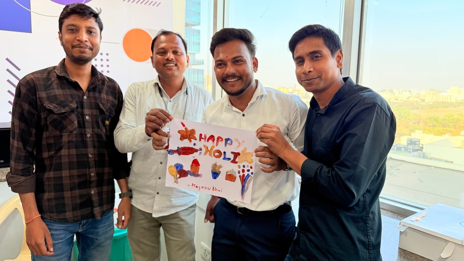 Flentas colleagues holding a Happy Holi sign at the office